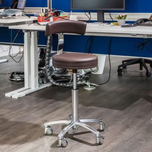 Bürohocker Jaques Scandic in Skai Sotega Mocca. Mit Basis Fußkreuz und Premium Rollen in silber. Mit Rückenlehne Banane Komfort.