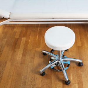 Praxishocker Rasmus Scandic in Skai Palma weiss. Pflegeleicht und desinfektionsmittelbeständig. Lange Gasfeder, Basis Fußkreuz, Stop-Rollen und Fußauslösung